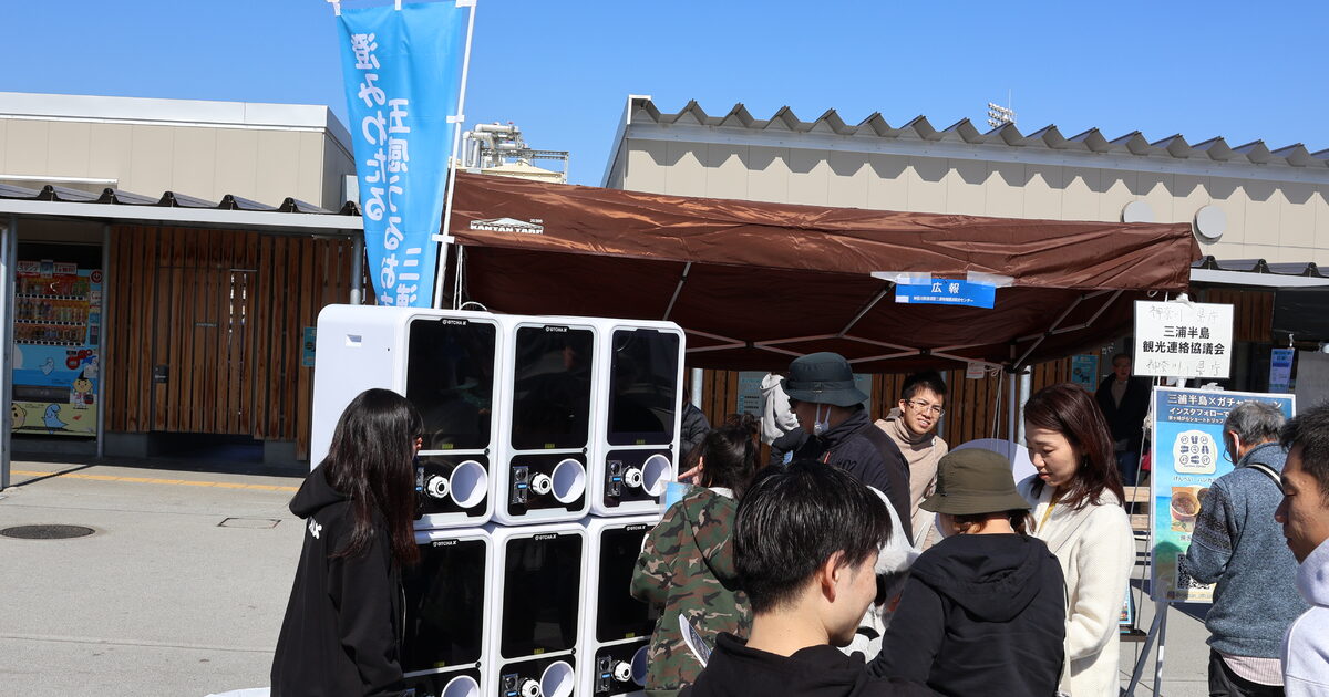 地域イベントの会場でガチャマシンに集まる来場者の賑わい
